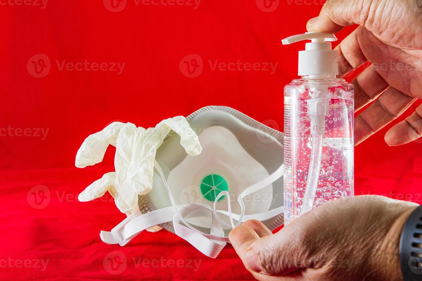 handen ontsmettingsgel witte latex handschoenen en masker op rood beschermingsconcept tegen vervuilingsvirusgriep en coronavirus foto