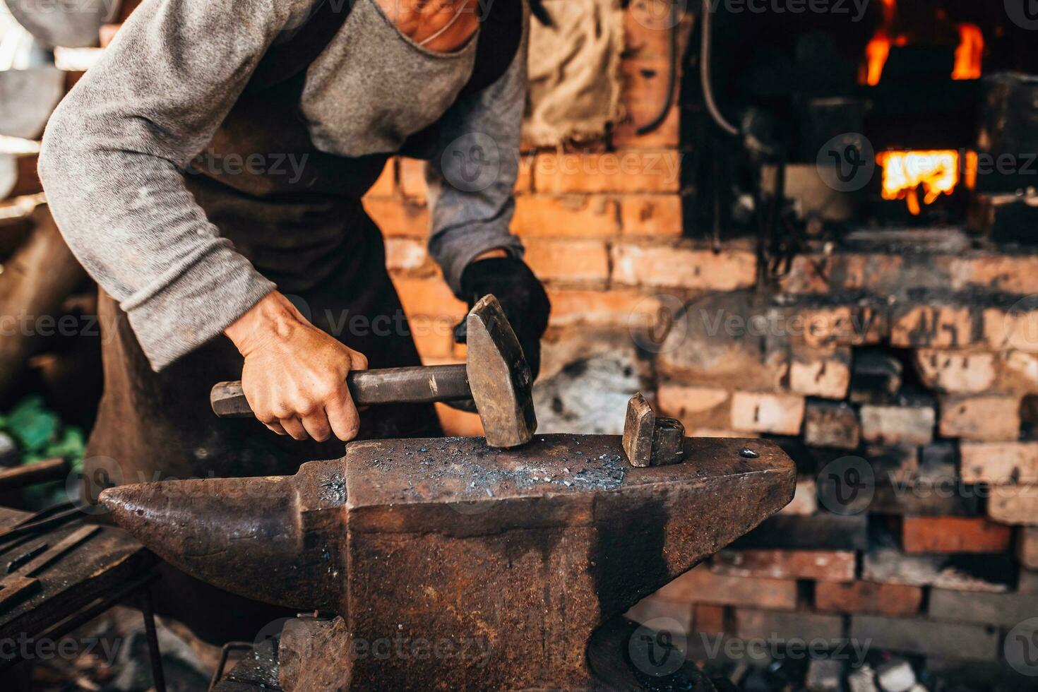 een mannetje smid smeedt door hand- in een smederij Aan een staal aambeeld - een oud ambacht foto