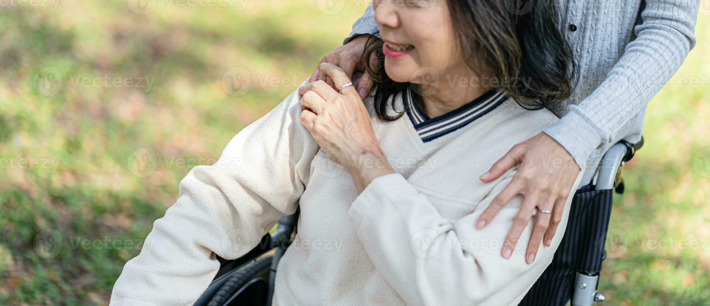 familie verhouding Aziatisch senior vrouw in rolstoel met gelukkig dochter Holding verzorger voor een hand- terwijl uitgeven tijd samen foto