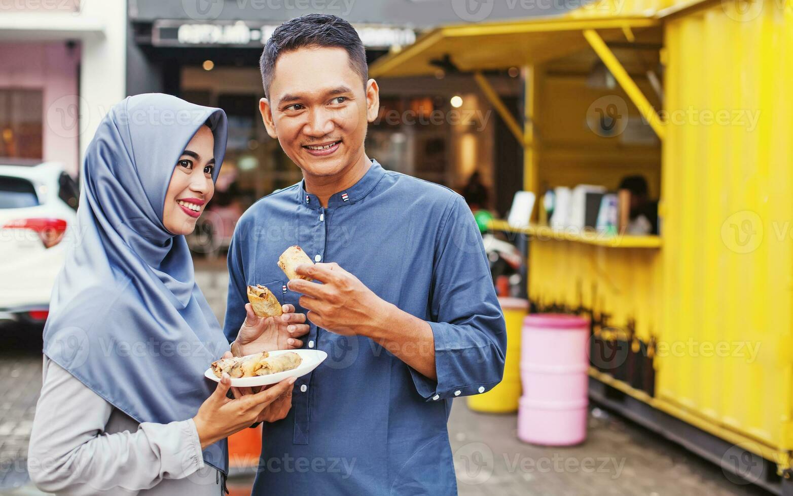 gelukkig moslim Indonesisch paar aan het eten rommel straat voedsel Aan de straat van Jakarta foto