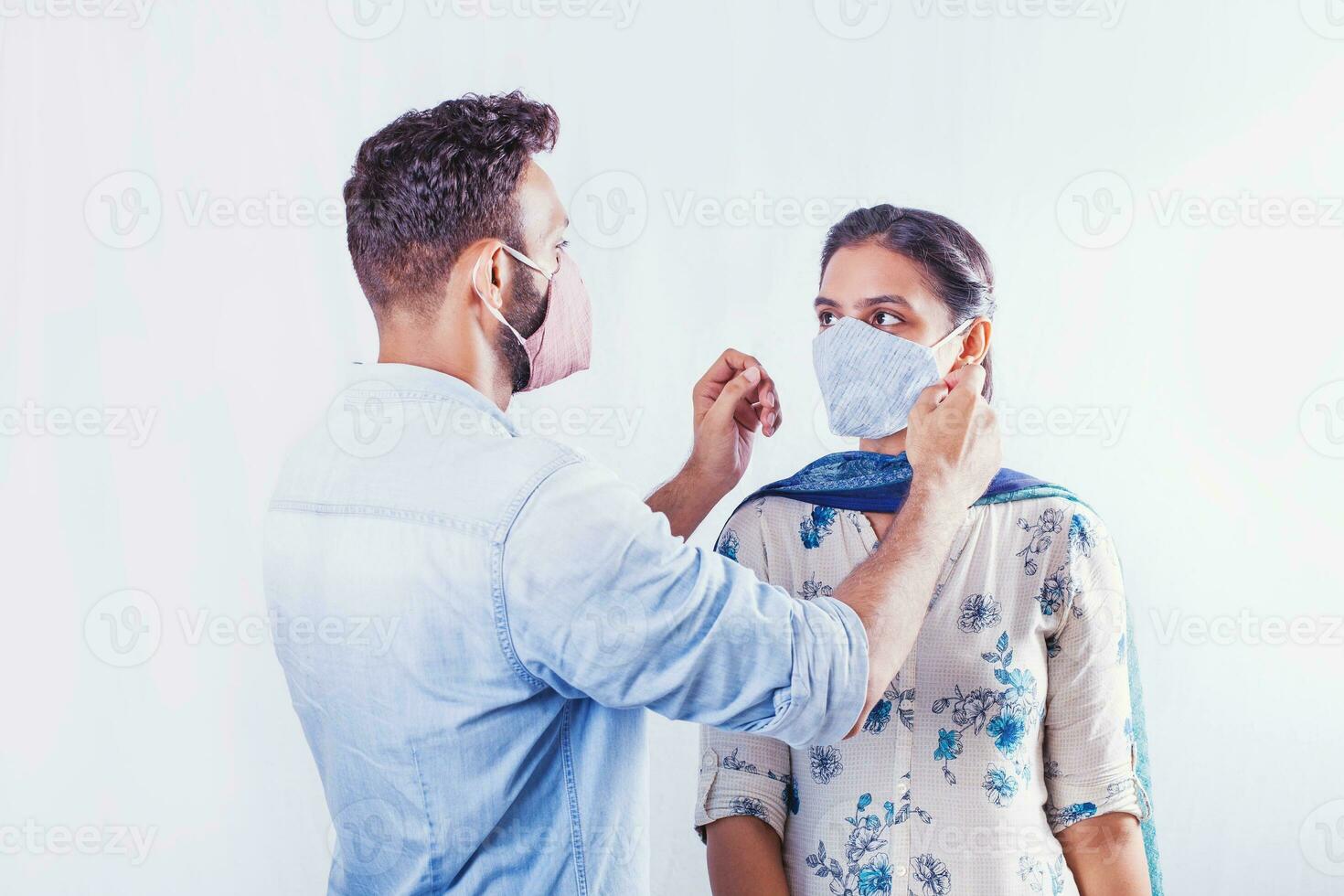 Indisch Mens zetten beschermend gezicht masker Aan een vrouw naar opslaan haar van covid-19 foto