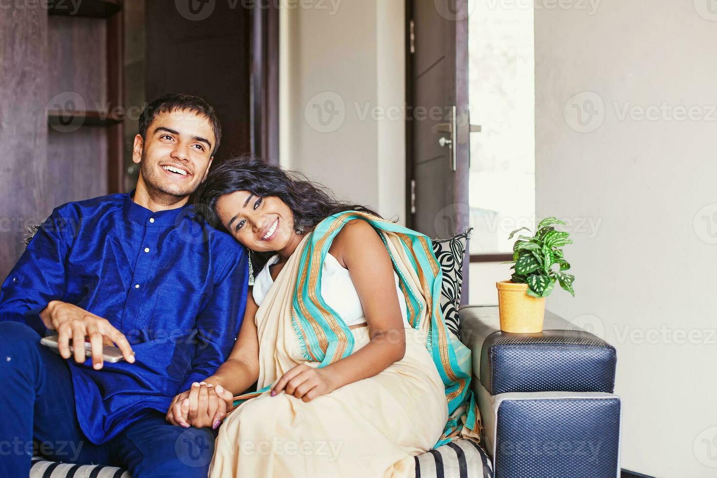 gelukkig getrouwd Indisch paar zittend Aan een sofa in hun eigen huis foto