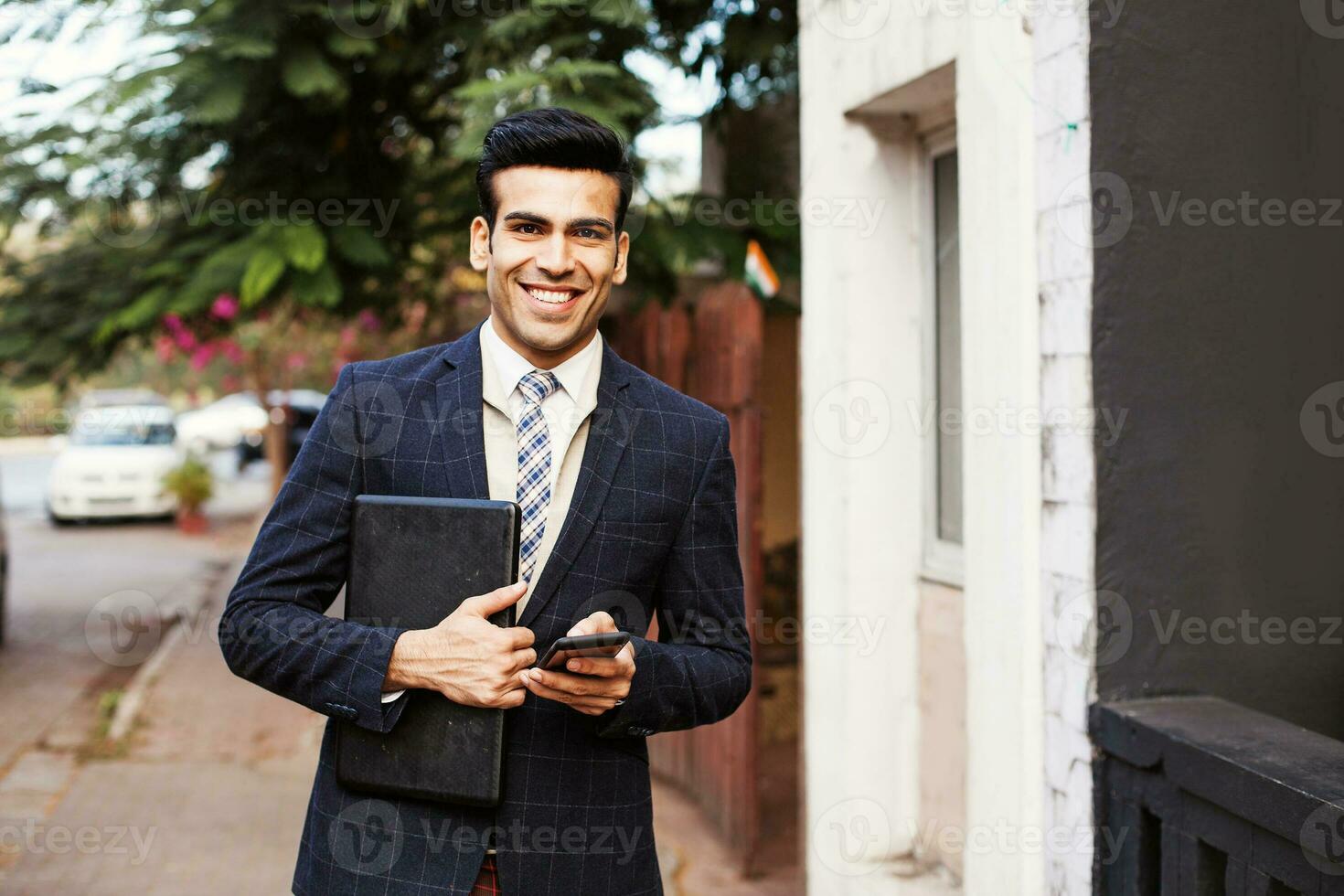knap Indisch Mens in bedrijf pak Holding laptop en mobiel telefoon foto