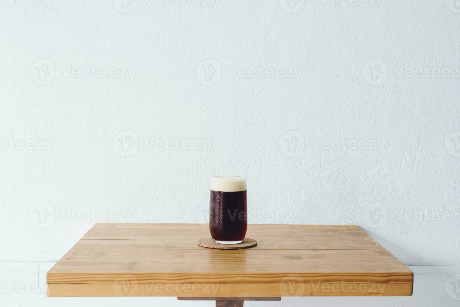 een drinken glas van verkoudheid brouwen dip koffie Aan de tafel met wit muur achtergrond. foto