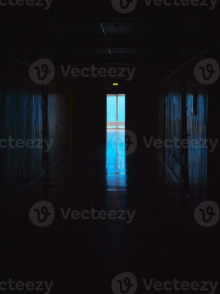 einde van donker tunnel met magie blauw licht. verticaal visie. leeg donker gang in ziekenhuis laboratorium. blauw licht Bij de einde van een donker hal. foto