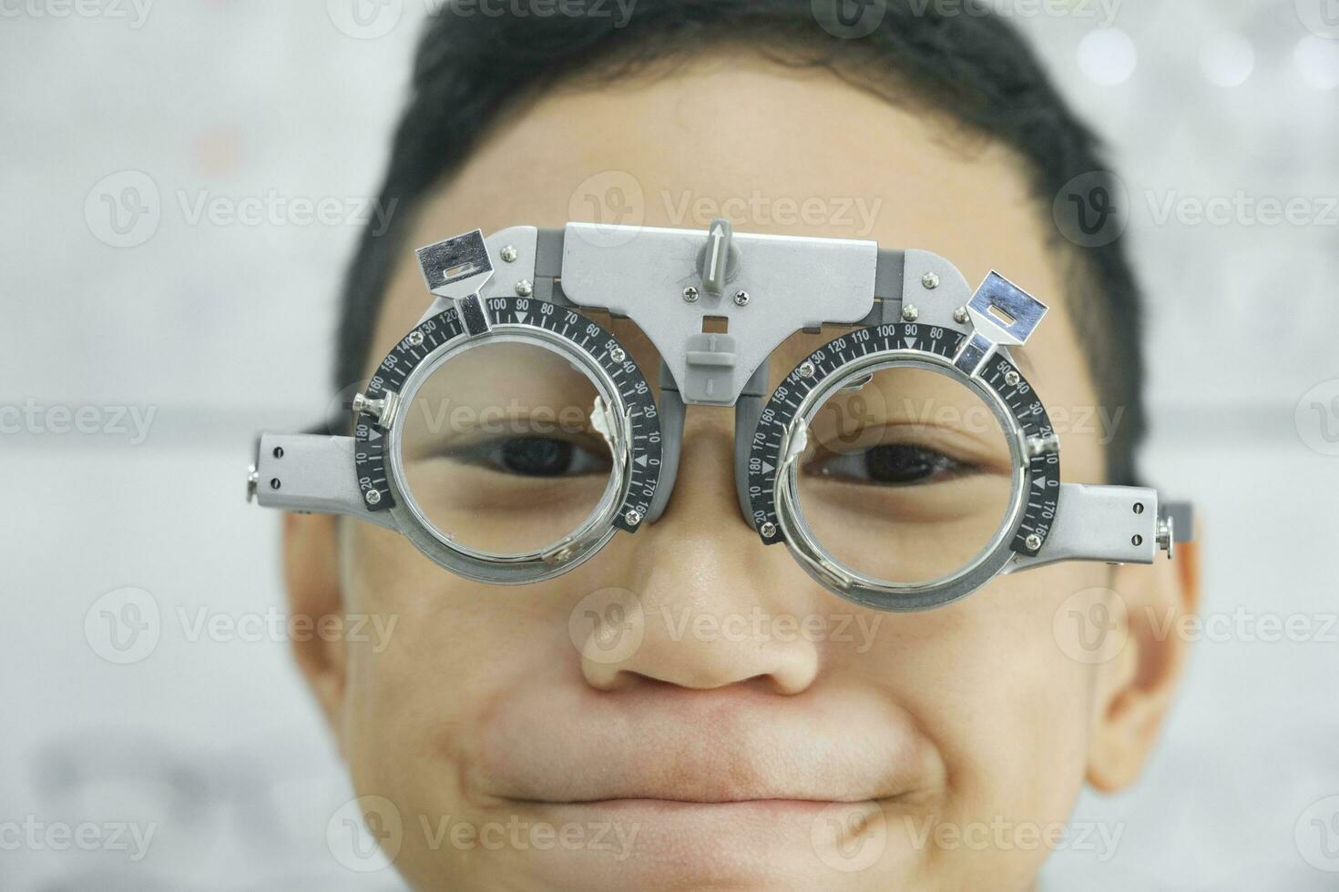 jong jongen onderzoeken gezichtsvermogen in optisch kliniek. foto