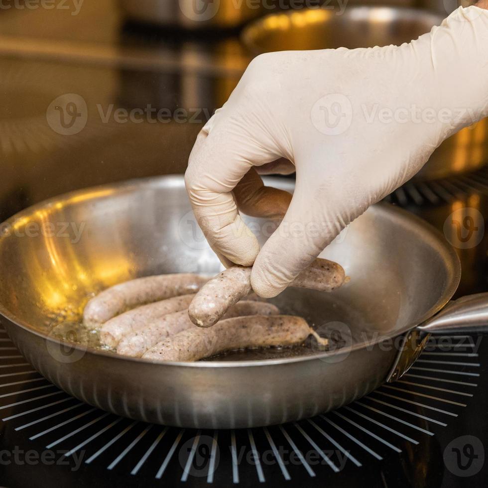 chef-kok die witte Duitse worstjes kookt foto