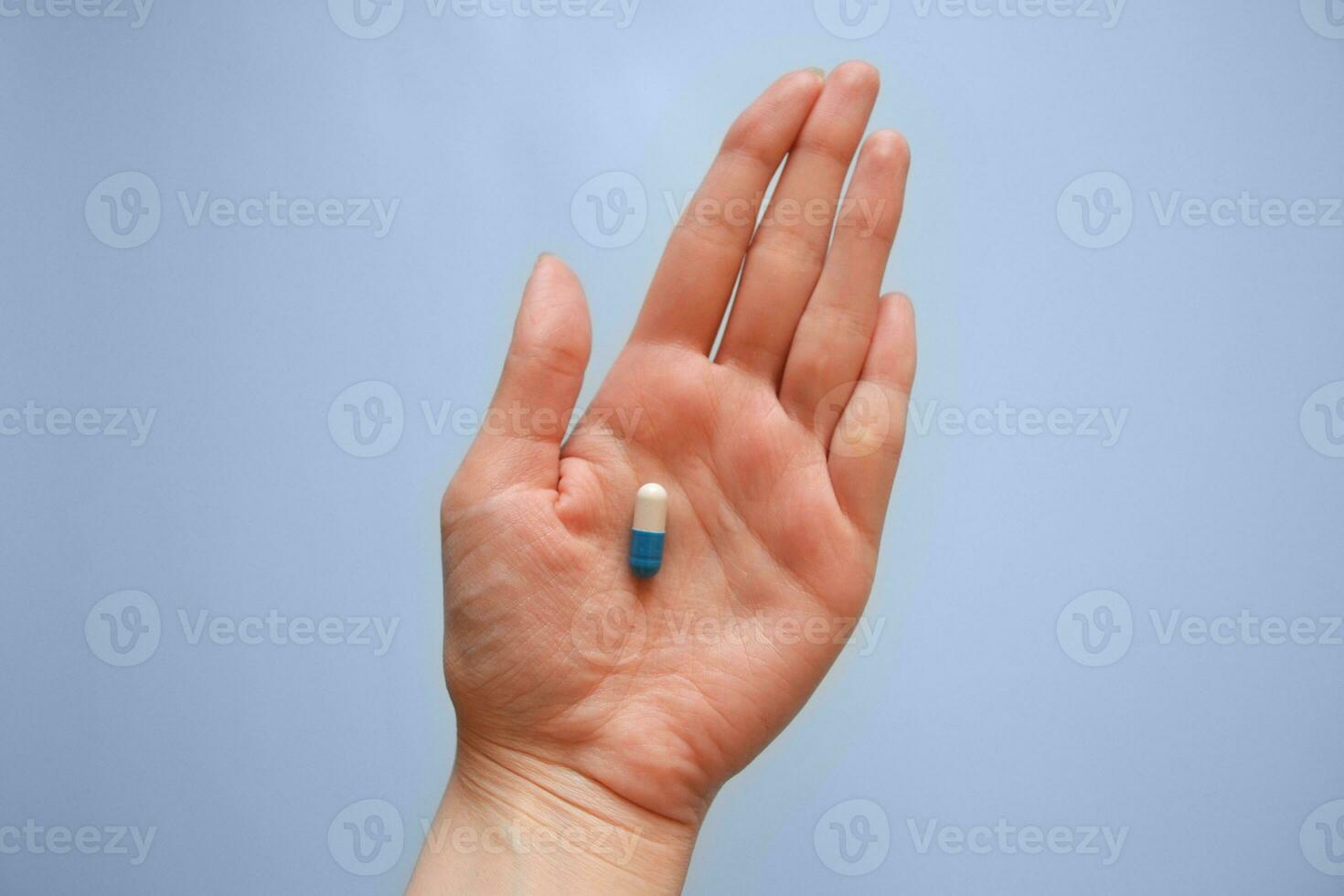 capsule Aan de palm van uw hand- Aan een blauw achtergrond, medicatie, dag van een medisch arbeider, medisch zorg foto