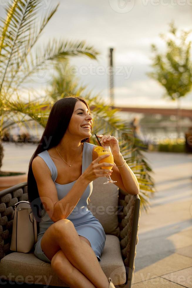 jonge vrouw sinaasappelsap drinken in het straatcafé foto