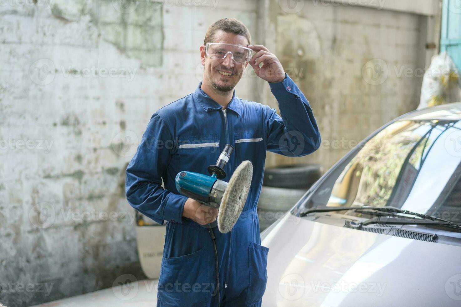 Kaukasisch Mens is gebruik makend van auto polijsten machine in reparatie monteur schilderij winkel foto