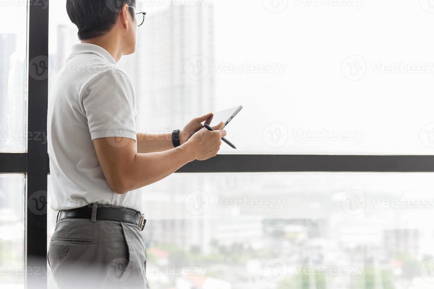 zakenman staande naast het raam met digitale tablet en digitale pen foto