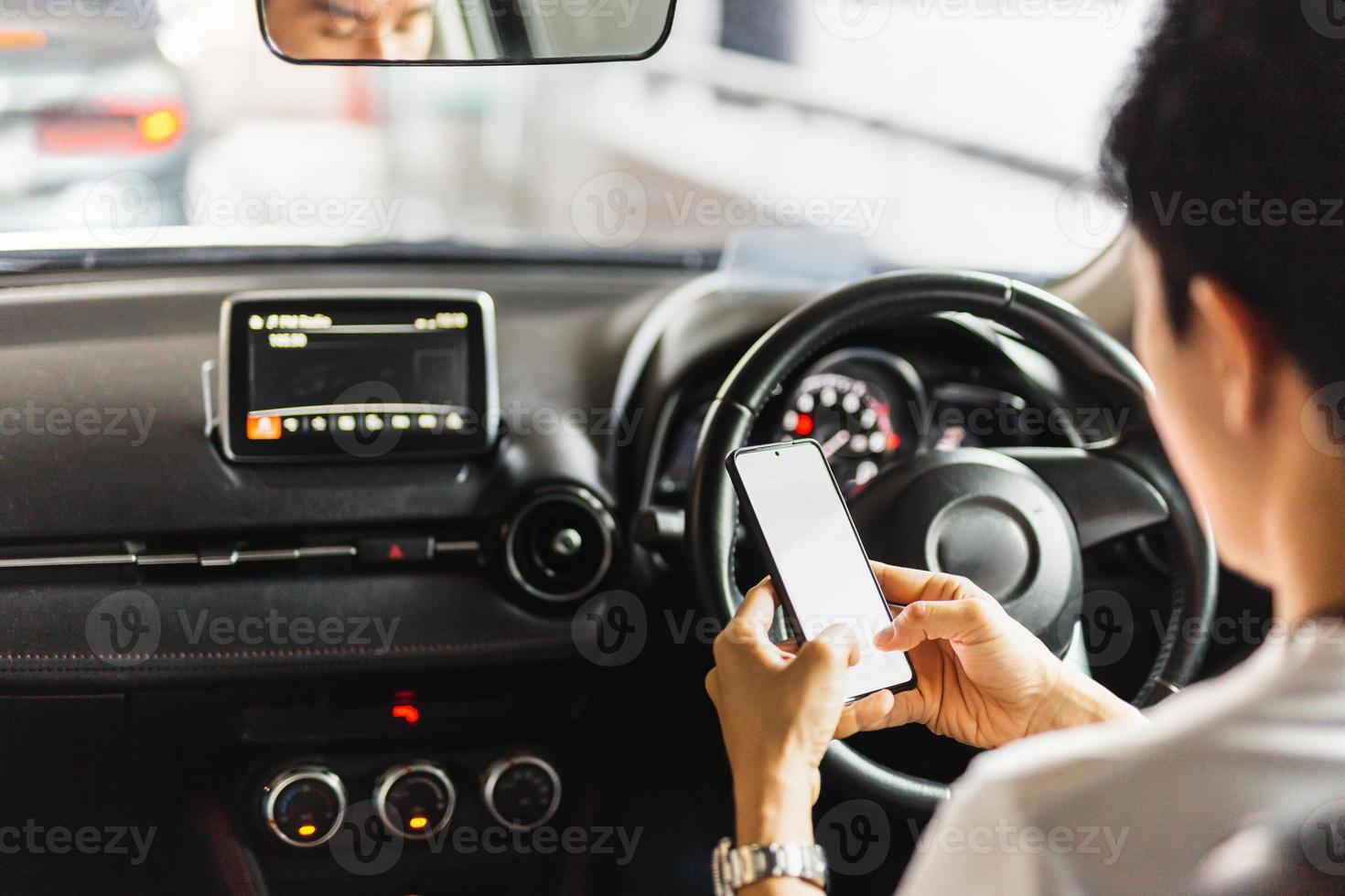 man met smartphone tijdens het autorijden foto