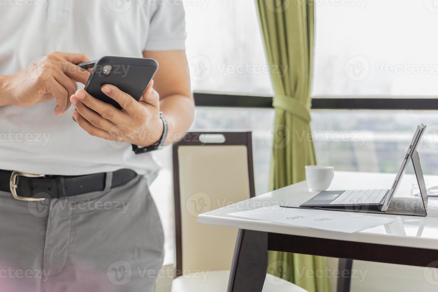 zakenman bezig met mobiele telefoon met laptop op tafel foto