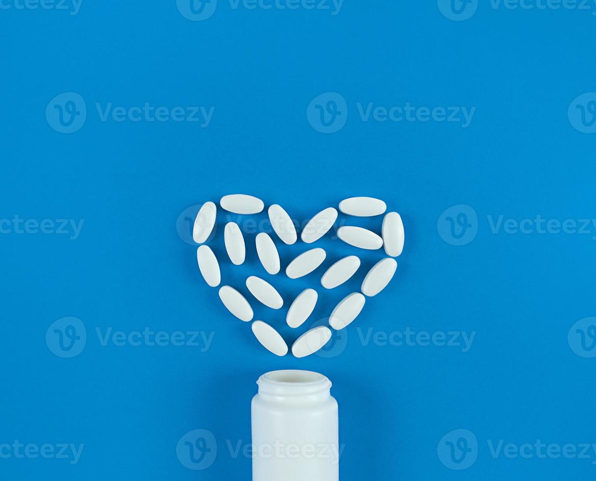 hartvorm gemaakt van witte tabletten en medische fles op blauwe achtergrond foto