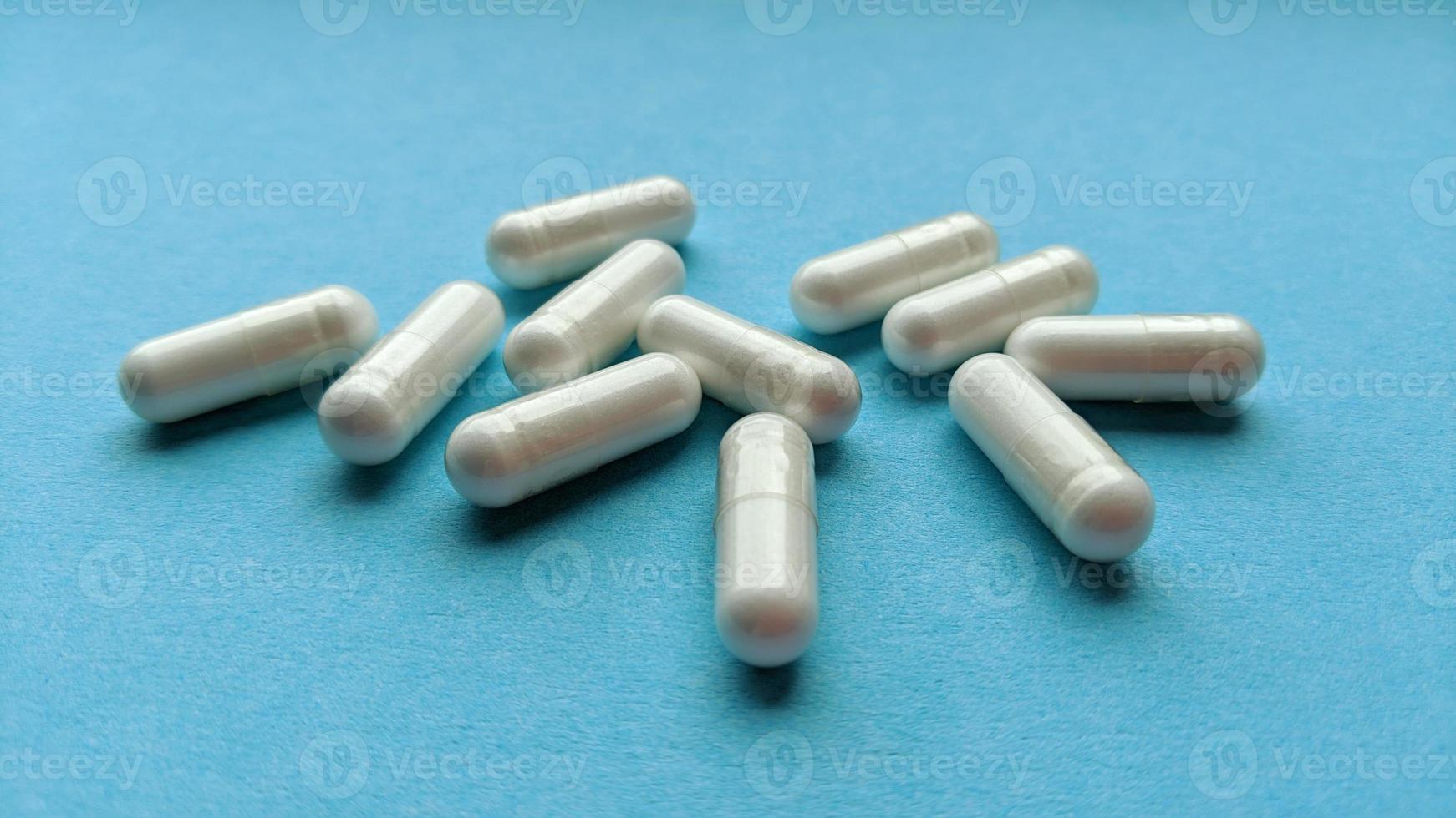 witte pil capsules op blauwe achtergrond eenvoudig plat leggen met pastel textuur medische concept stock foto
