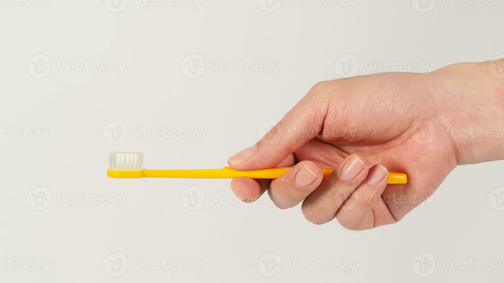 hand- Holding geel tandenborstel Aan wit achtergrond. foto