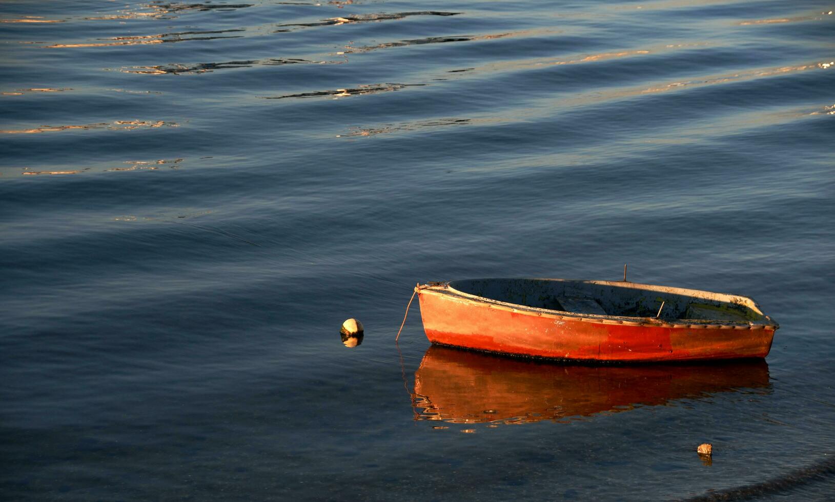 klein oranje boot verankerd Aan de kust foto