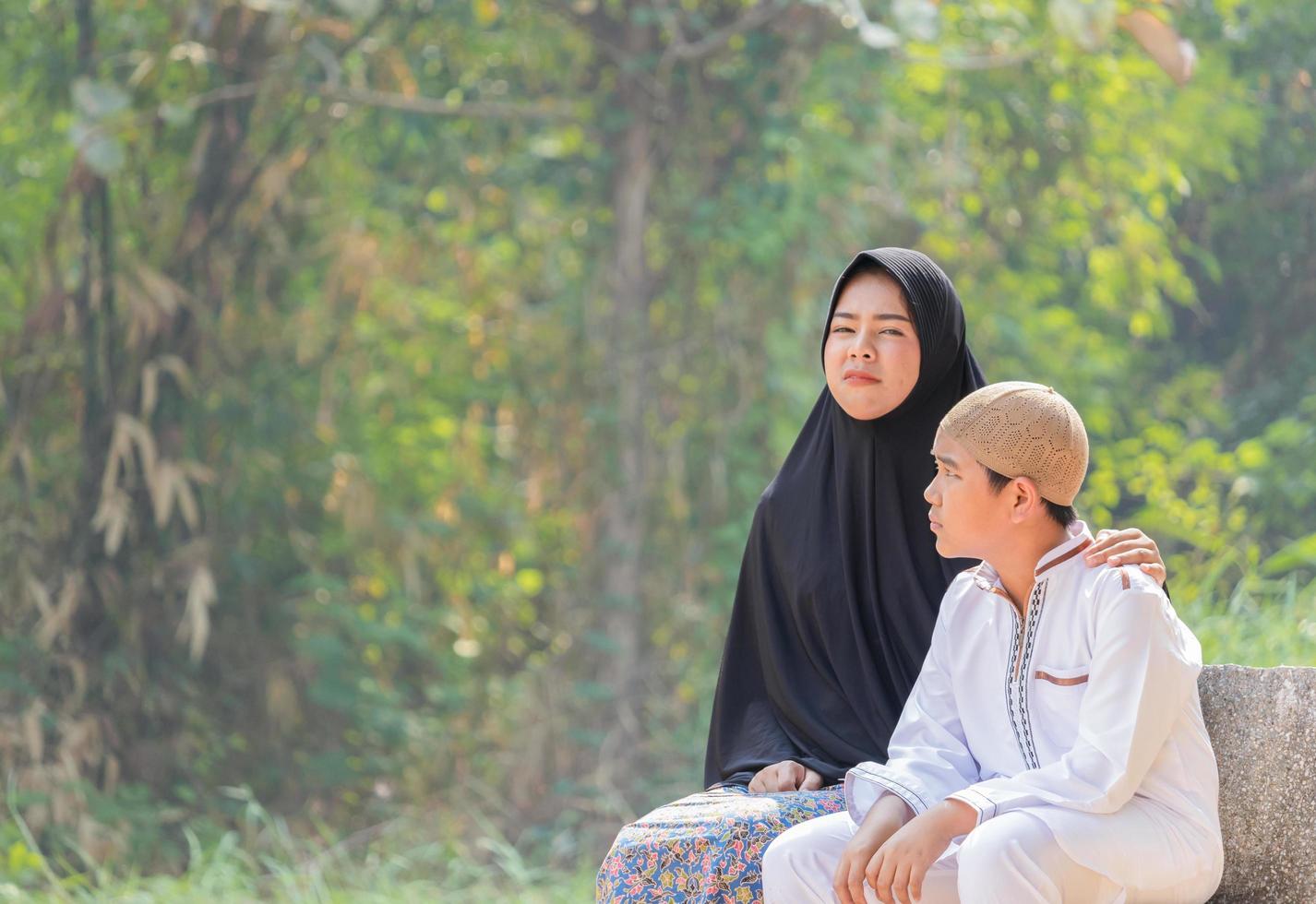 moslimmoeder en zoon zitten 's ochtends op een tuinbank foto