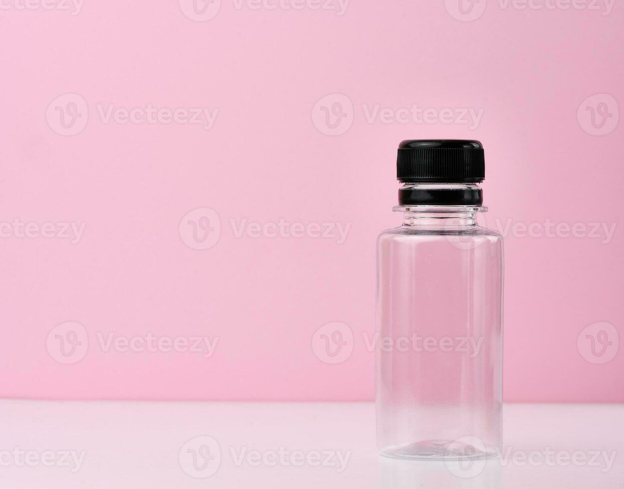 leeg plastic fles met zwart pet Aan roze achtergrond foto