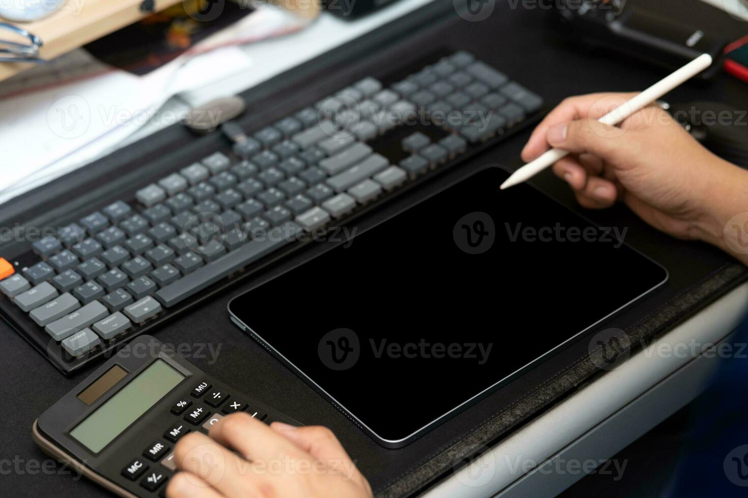 hand- met stylus pen schrijven Aan tablet met donker scherm en de andere hand- gebruik makend van rekenmachine. foto