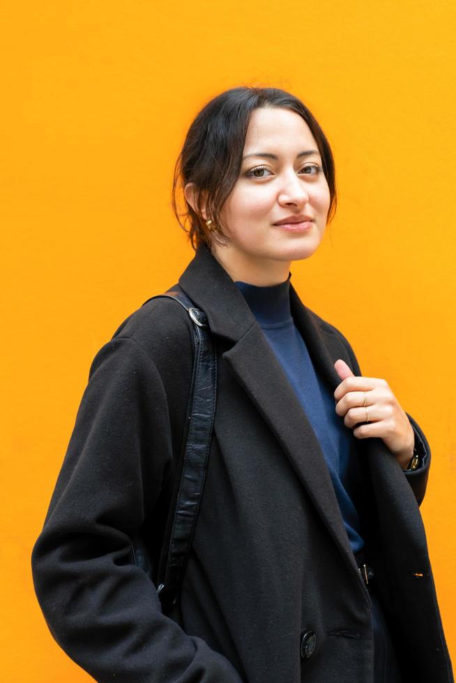 jong mooi Arabisch meisje poseert voor oranje muur met slimme, elegante kleding foto