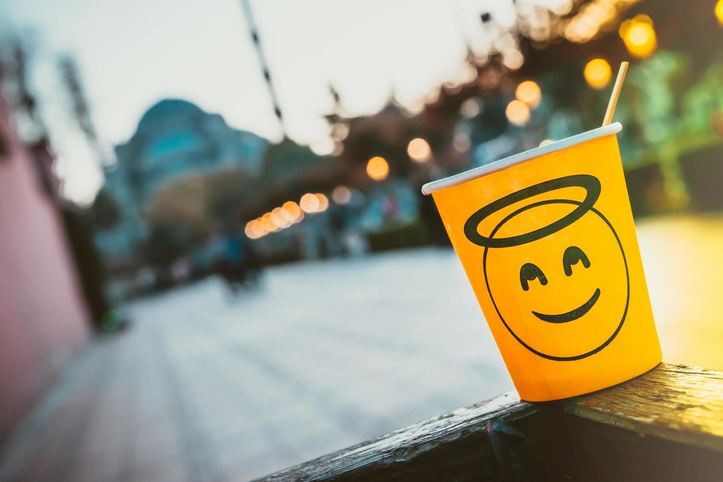 kartonnen beker met smileygezicht achtergelaten op straat met wazige moskee op de achtergrond foto