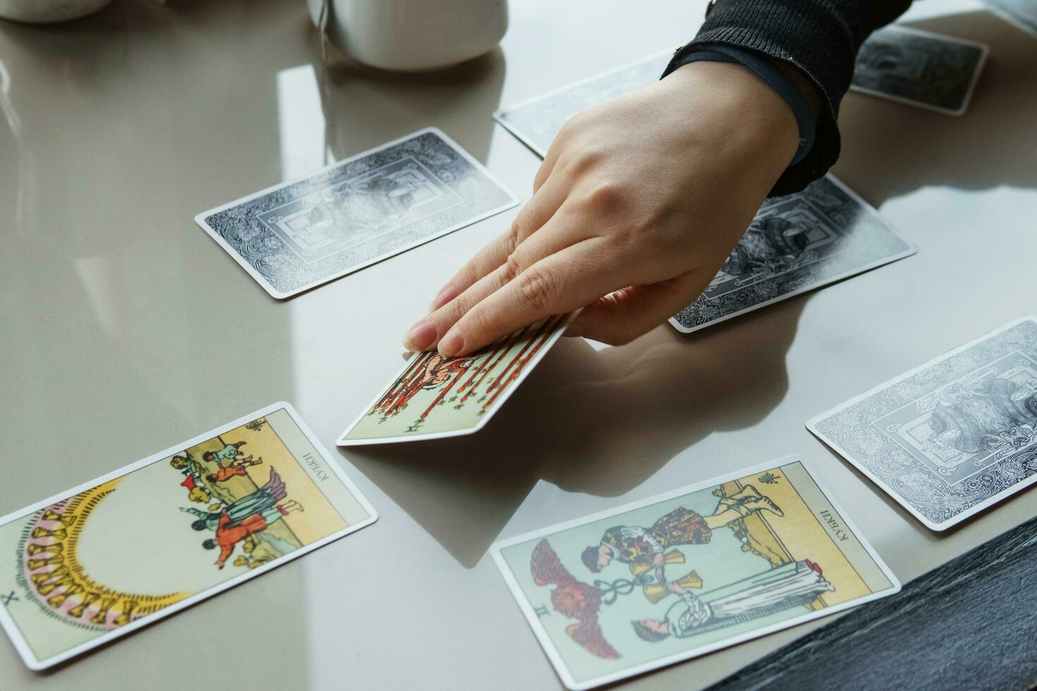 tver, Rusland - februari 11, 2023. tarot kaarten, tarot kaart waarzeggerij, esoterisch achtergrond. een vrouw maakt een lay-out Aan de kaarten Bij de tafel. waarzeggerij, voorspellingen Aan tarot kaarten. foto