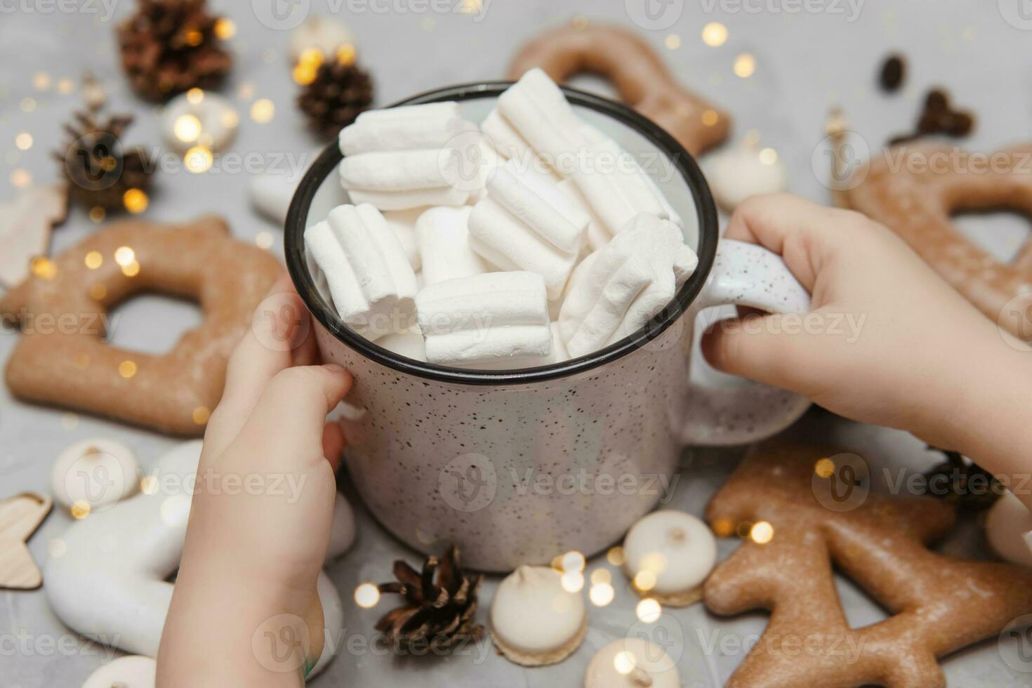 kinderen handen houden een kop van cacao met marshmallows. Kerstmis peperkoek Aan de tafel, bokeh lichten in de voorgrond. de concept van desserts en drankjes gedurende de Kerstmis vakantie. foto