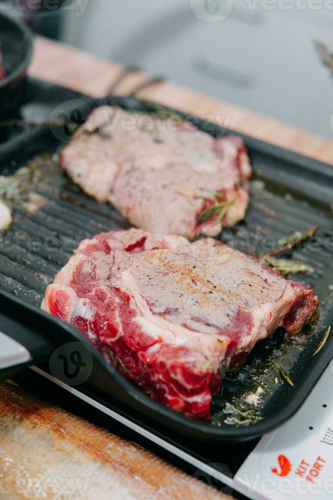 Koken steaks in een pan. Koken rundvlees Bij de culinaire meester klas. de handen van de chef in zwart handschoenen. foto