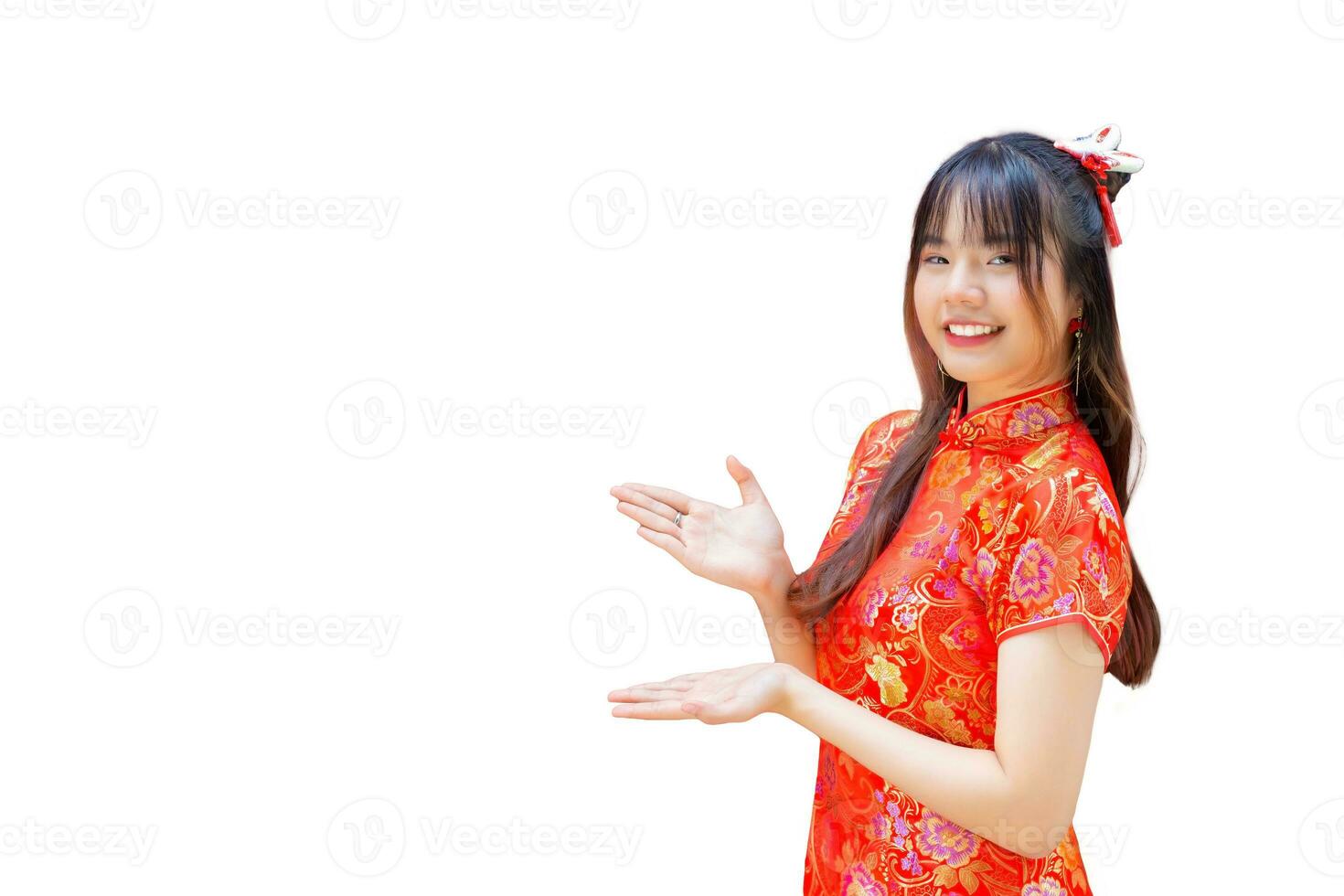 schattig Aziatisch meisje met lang haar- wie draagt een rood cheongsam jurk in Chinese nieuw jaar thema terwijl ze shows haar hand- naar Cadeau iets Aan een rood achtergrond. foto