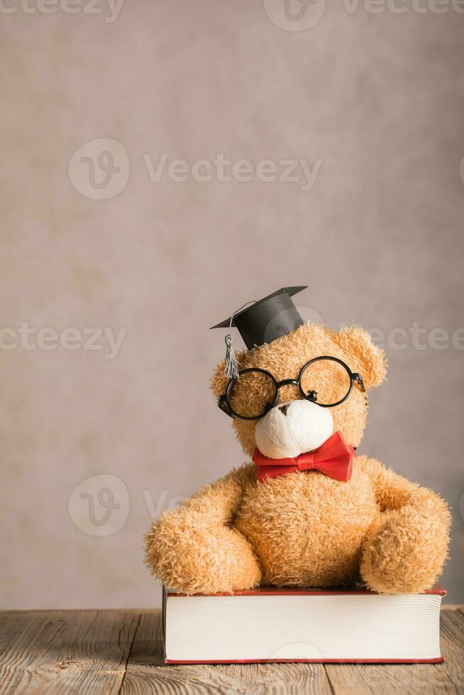 bruin teddy beer in een academisch pet is geplaatst Aan een dik woordenboek. foto