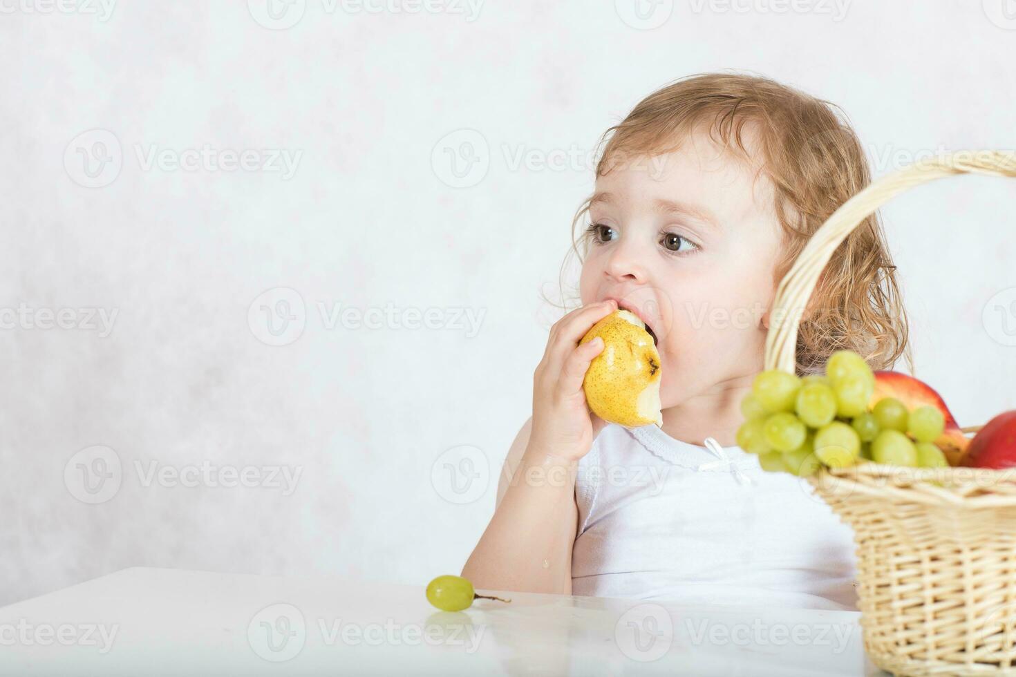 klein meisje is aan het eten vers fruit van een tafel. detailopname foto