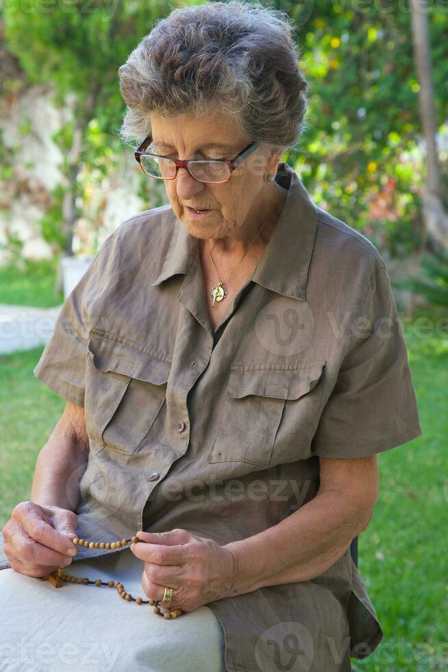 een oud vrouw is bidden in de tuin foto