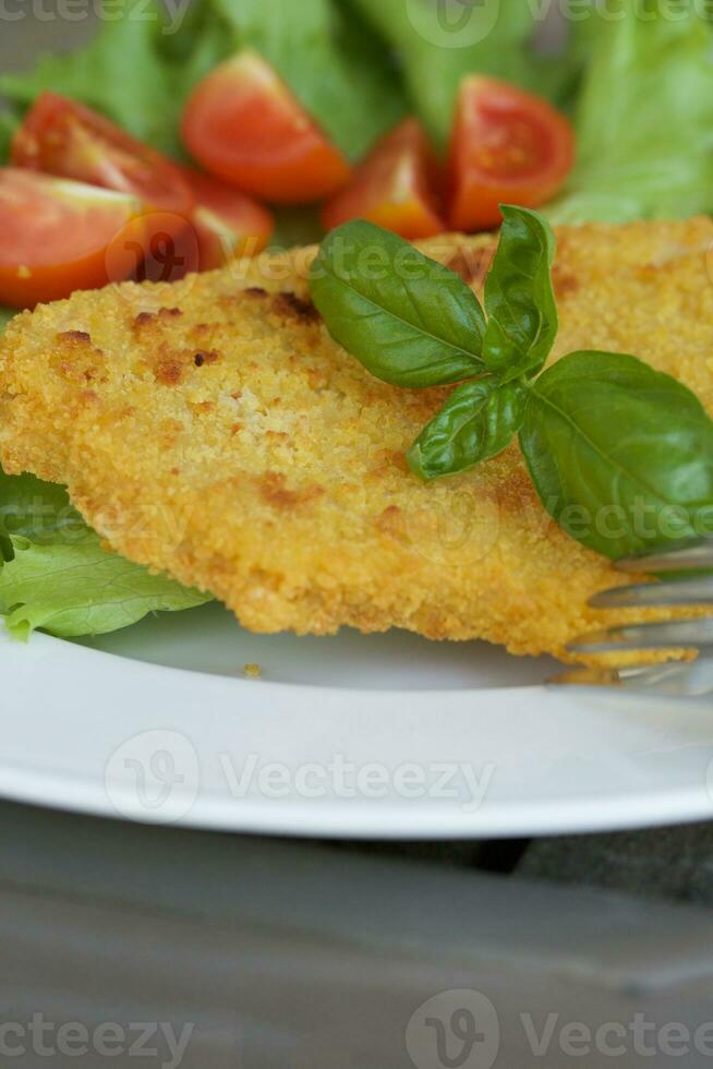 kip schnitzel met kers tomaten en groen salade bladeren. foto