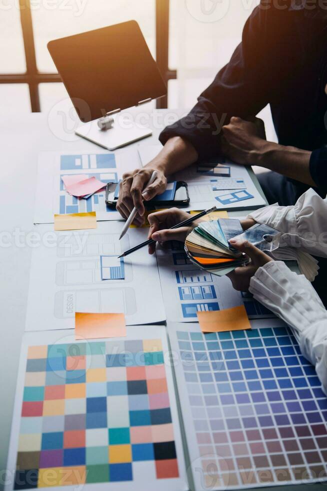 dichtbij omhoog ux ontwikkelaar en ui ontwerper brainstorming over mobiel app koppel wireframe ontwerp Aan tafel met klant breif en kleur code Bij modern kantoor.creatief digitaal ontwikkeling agentschap foto