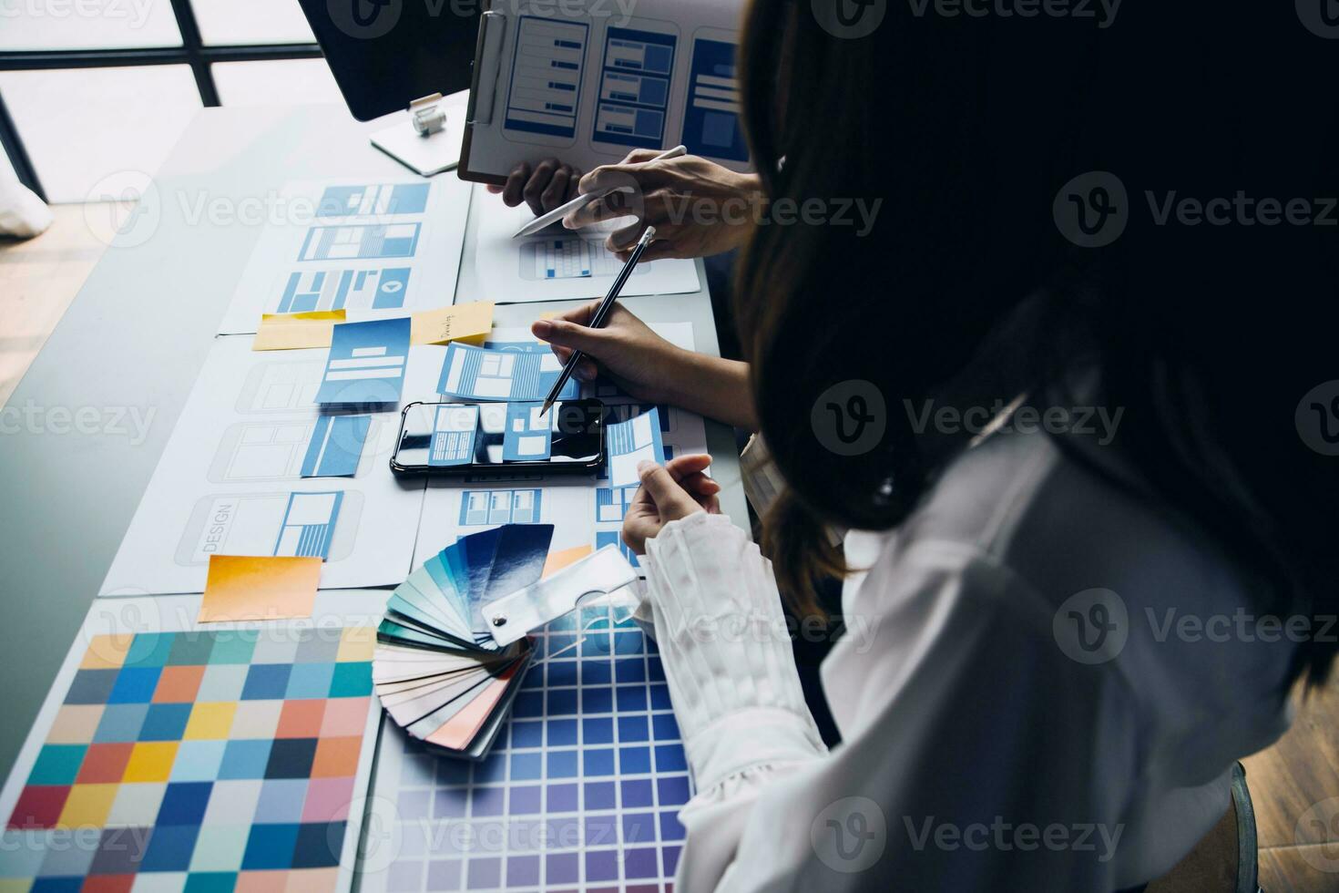 dichtbij omhoog ux ontwikkelaar en ui ontwerper brainstorming over mobiel app koppel wireframe ontwerp Aan tafel met klant breif en kleur code Bij modern kantoor.creatief digitaal ontwikkeling agentschap foto
