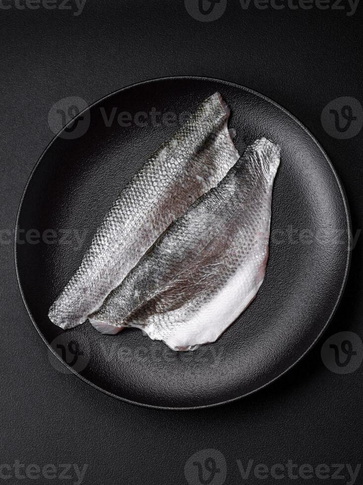 rauw zee bas vis filet met zout, specerijen en kruiden Aan een keramisch bord foto