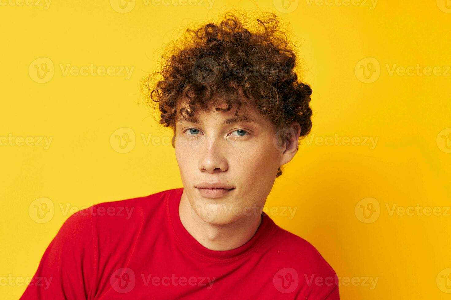 portret van een jong gekruld Mens rood t overhemd pret poseren gewoontjes slijtage geïsoleerd achtergrond ongewijzigd foto