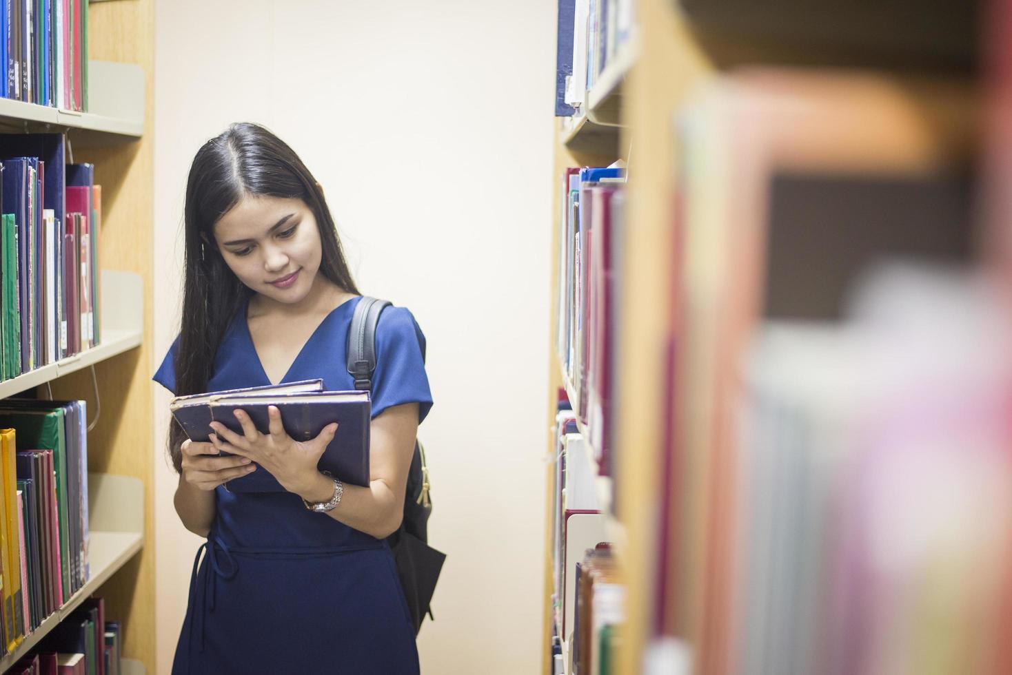 aantrekkelijke vrouwelijke Aziatische universiteitsstudent leesboek in bibliotheek foto