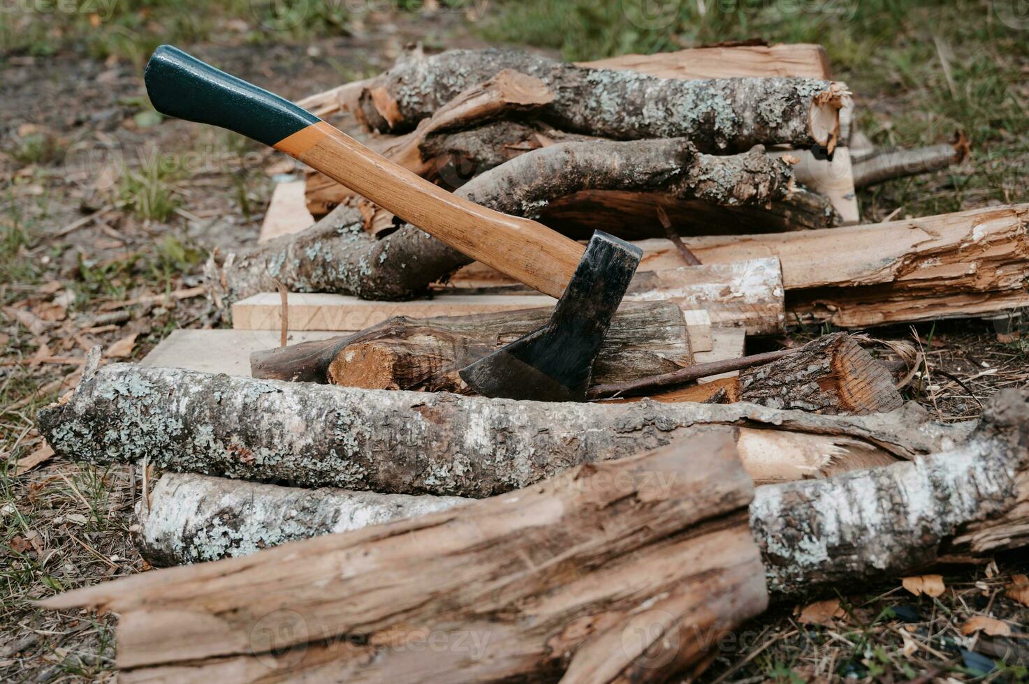 een oud gehavend bijl is zit vast in een log Aan een stapel van brandhout. buitenshuis recreatie. voorbereiding voor de vreugdevuur. foto