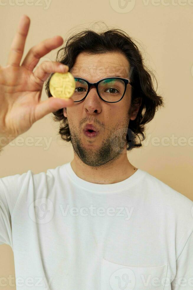vrolijk Mens met bril goud bitcoin in handen beige achtergrond foto