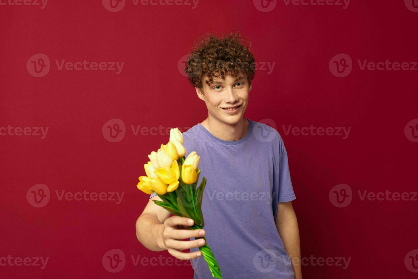 een jong Mens Holding een geel boeket van bloemen Purper t-shirts geïsoleerd achtergrond ongewijzigd foto