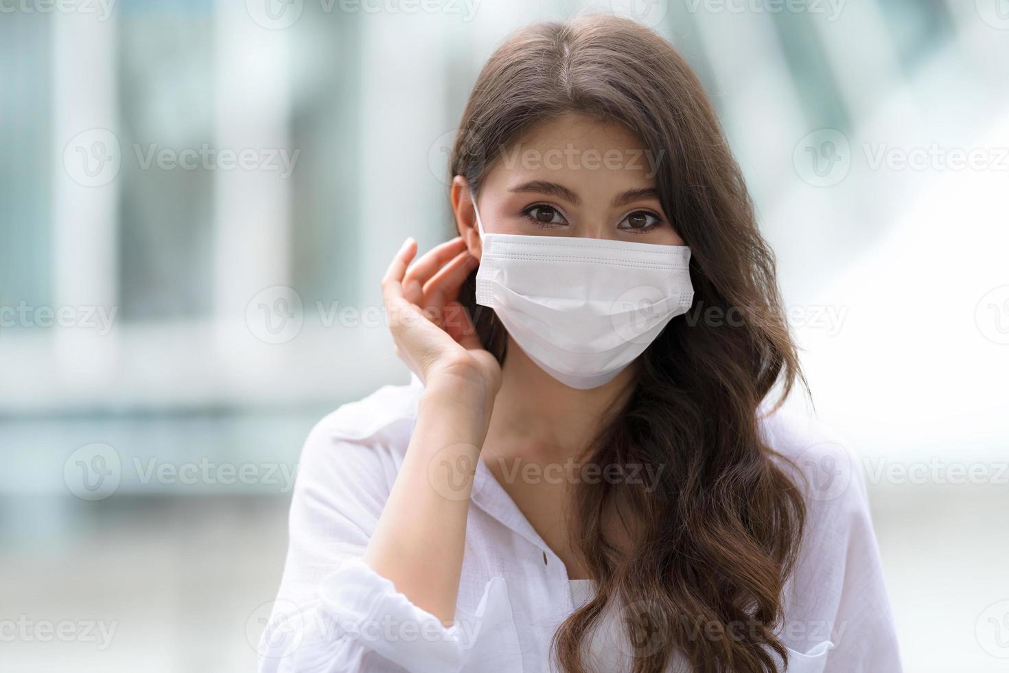 portret van een jonge vrouw met smiley gezicht dragen gezichtsmasker beschermende wandelingen in een stad foto