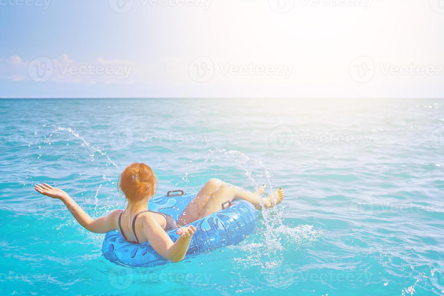 roodharige meisje spatten water in de cirkel zwemmen foto
