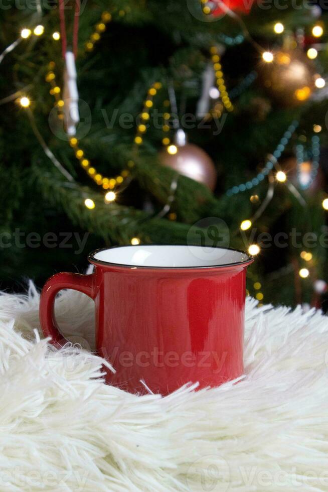 blanco rood mok met Kerstmis boom Aan achtergrond, thee of koffie kop met Kerstmis en nieuw jaar decoratie, horizontaal bespotten omhoog met keramisch mok voor heet drankjes, leeg geschenk afdrukken sjabloon foto