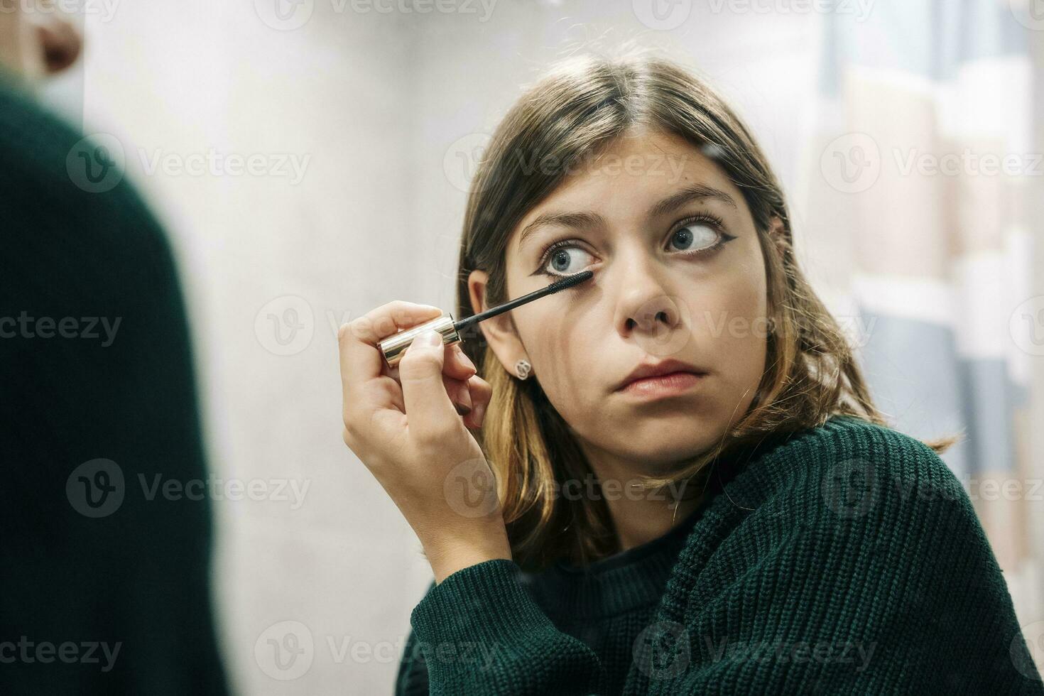 dichtbij omhoog reflectie van tiener- meisje toepassen mascara Aan wimpers foto