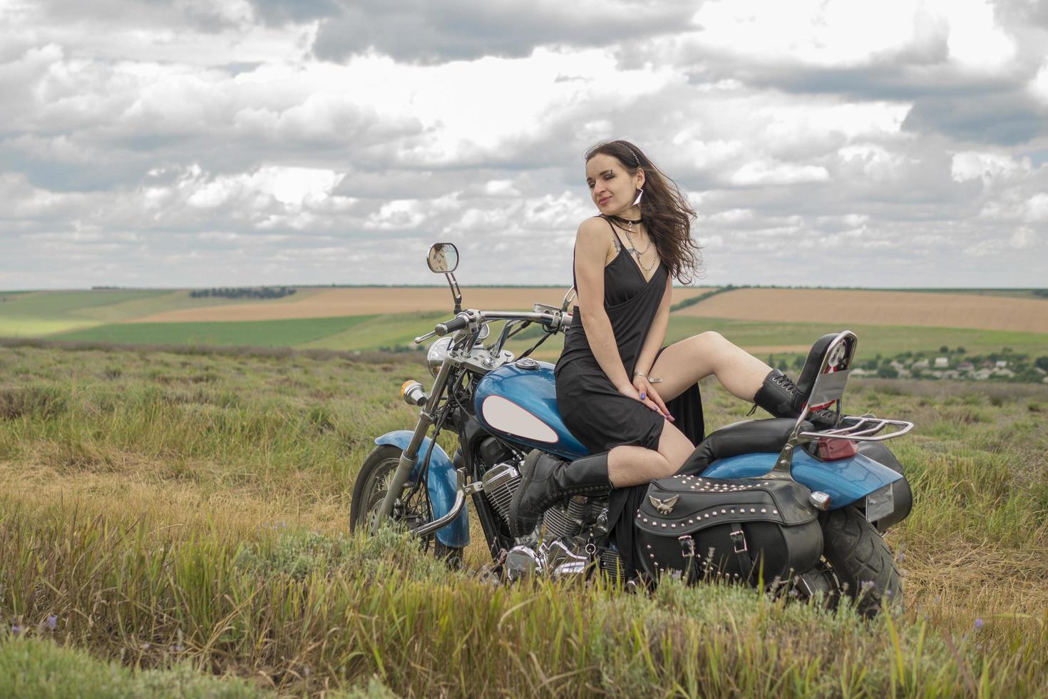 brunette fietser op een motorfiets in zwart lederen jas lavendelveld tegen de hemel met wolken slow motion foto