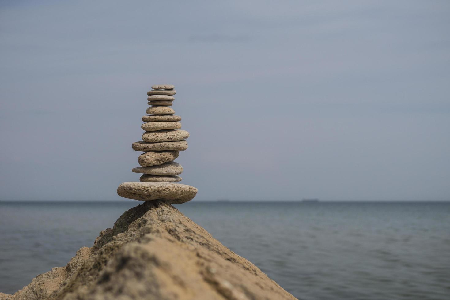 balancerende piramide van stenen op een grote steen aan de kust foto