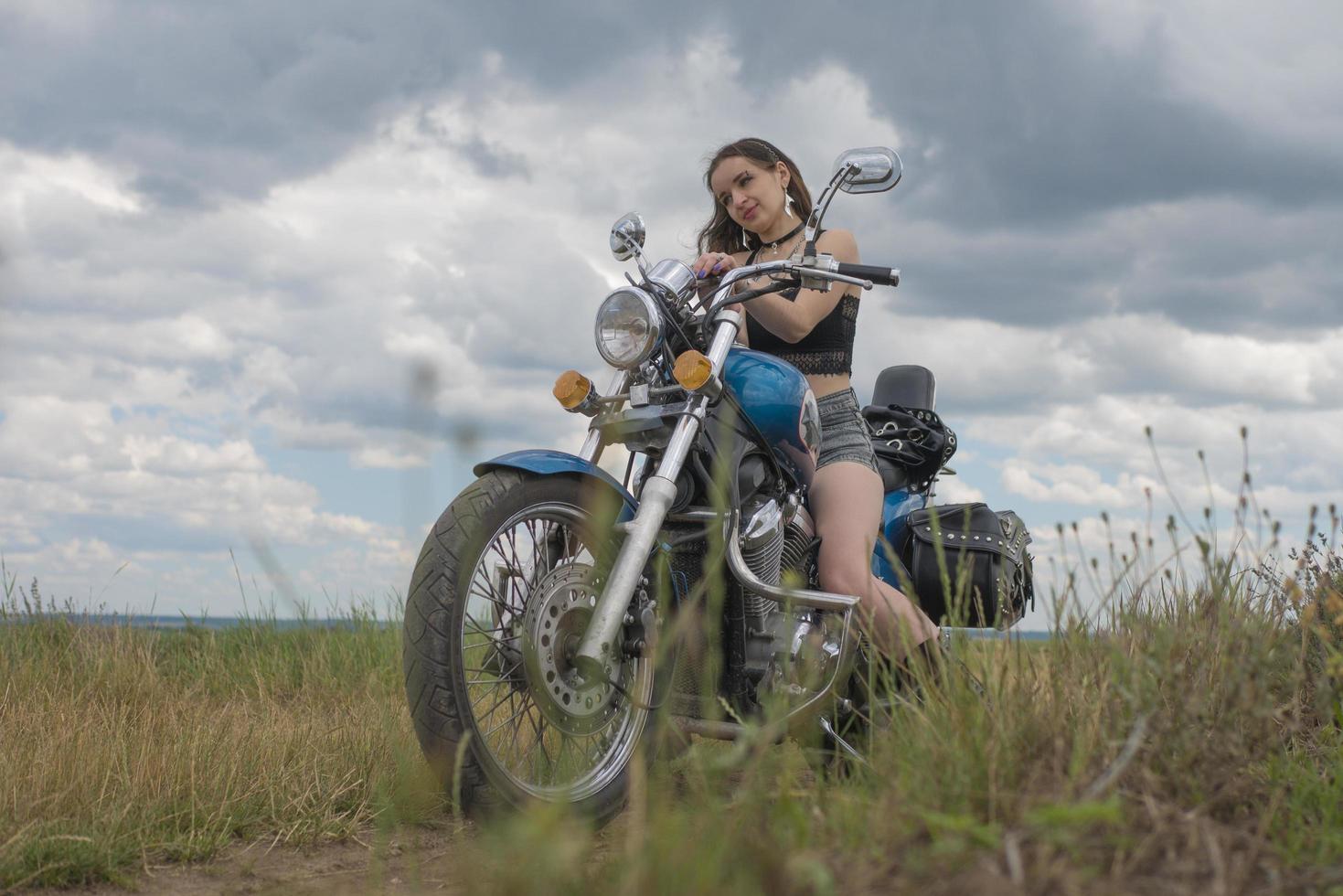 brunette fietser op een motorfiets in zwart lederen jas lavendelveld tegen de hemel met wolken foto