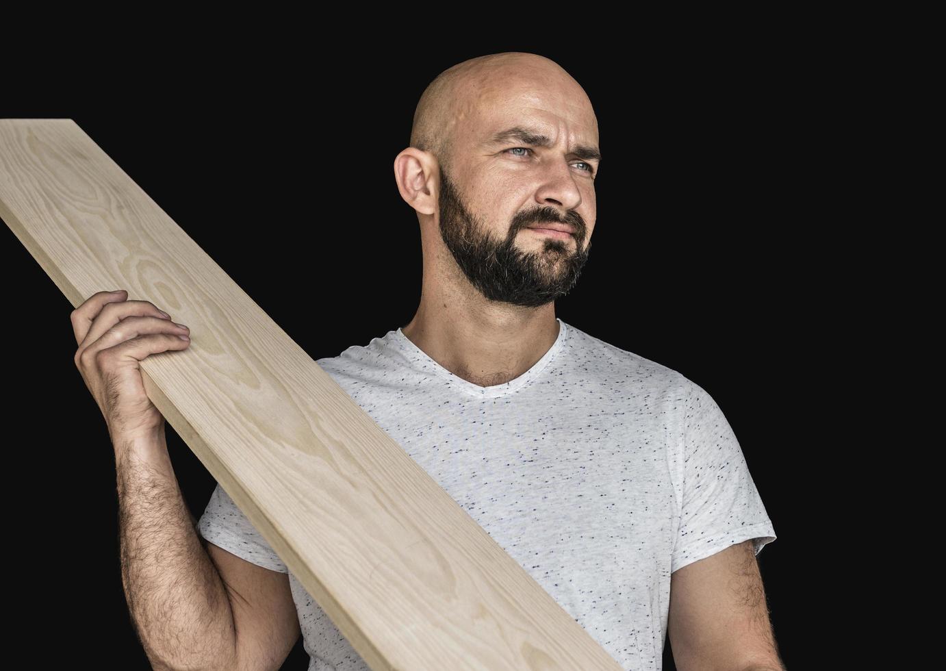 een timmerman in een wit t-shirt met een bord bij de hand wegkijken op een zwarte achtergrond isoleren foto